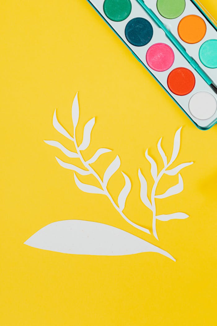 Artistic paper cutout with vibrant watercolor palette on yellow background.